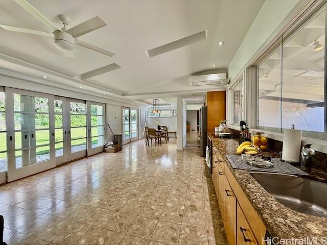 kitchen with sink, stainless steel refrigerator, dark stone countertops, french doors, and an AC wall unit