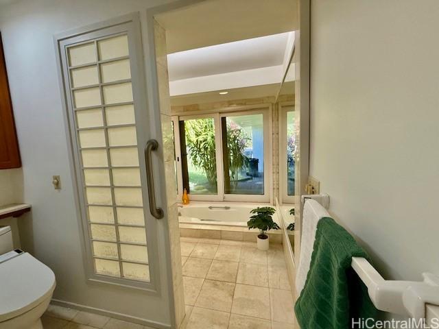 bathroom featuring tile patterned flooring, a tub, and toilet