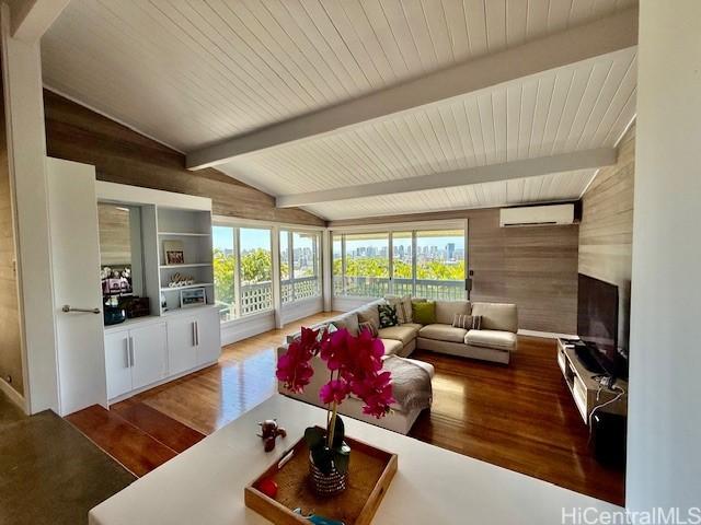 living room featuring vaulted ceiling with beams, wooden walls, a wall unit AC, and hardwood / wood-style floors