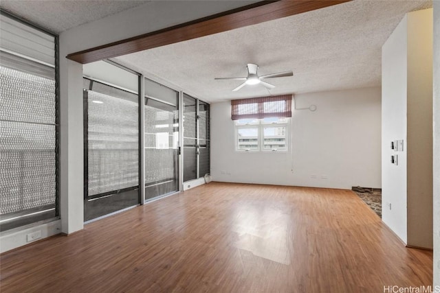 spare room with hardwood / wood-style flooring, ceiling fan, a textured ceiling, and a wall of windows