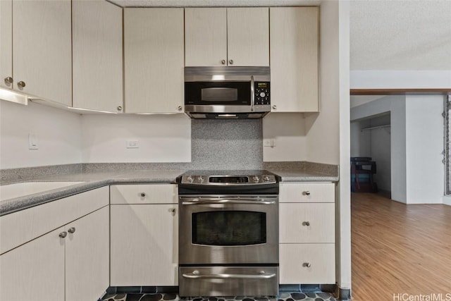 kitchen featuring stainless steel appliances, wood-type flooring, and cream cabinetry