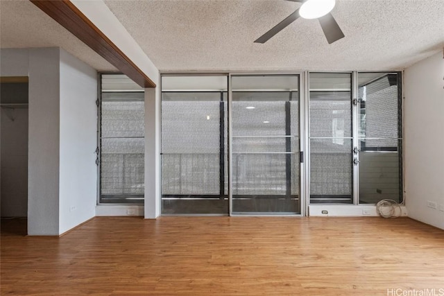 unfurnished bedroom with ceiling fan, floor to ceiling windows, hardwood / wood-style floors, and a textured ceiling