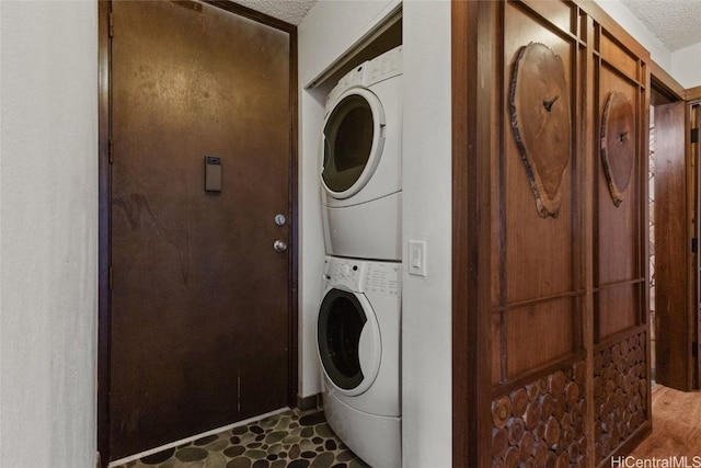 laundry room featuring stacked washer / drying machine and a textured ceiling