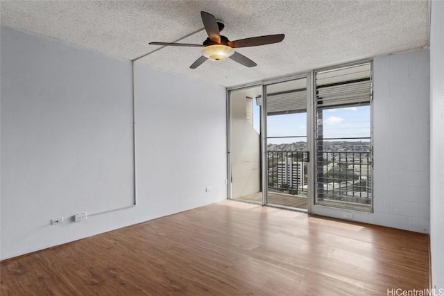 spare room featuring hardwood / wood-style floors, expansive windows, a textured ceiling, and ceiling fan