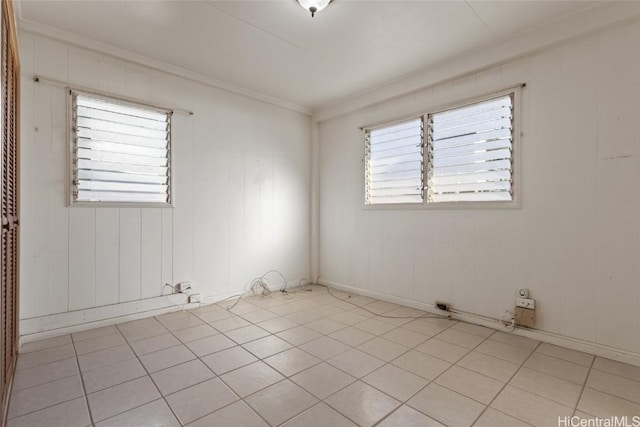 tiled spare room featuring ornamental molding