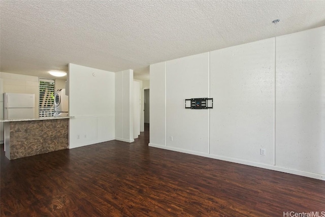 spare room with dark hardwood / wood-style flooring, washer / dryer, and a textured ceiling