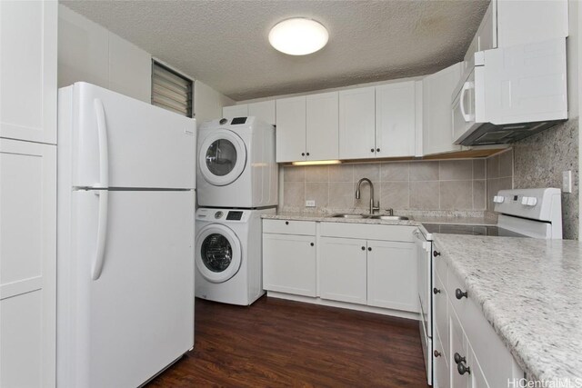 laundry room featuring sink, dark hardwood / wood-style floors, stacked washer and clothes dryer, and a textured ceiling