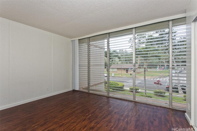 spare room with expansive windows, plenty of natural light, a textured ceiling, and dark hardwood / wood-style flooring