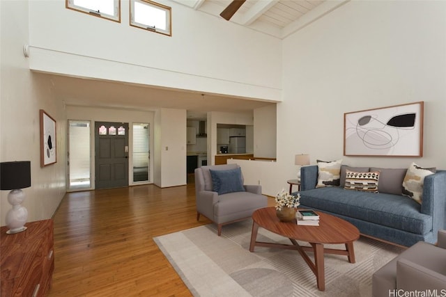 living room featuring dark wood-type flooring, a towering ceiling, and beamed ceiling