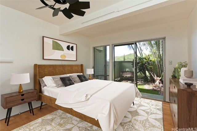 bedroom with ceiling fan, access to outside, light hardwood / wood-style floors, and beamed ceiling