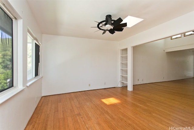 empty room with built in shelves, light hardwood / wood-style floors, and ceiling fan