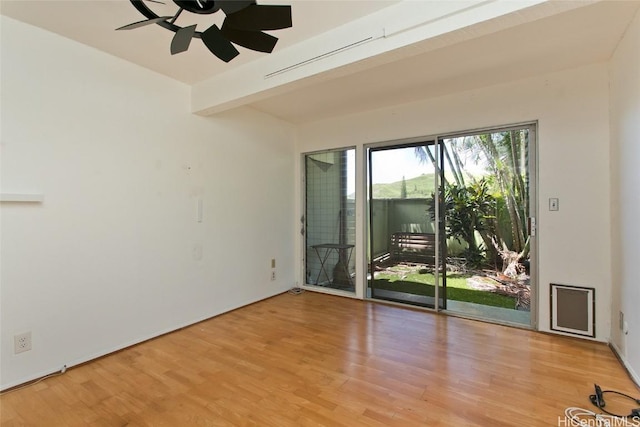 empty room with beam ceiling, ceiling fan, and light wood-type flooring