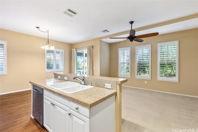 kitchen with pendant lighting, white cabinetry, an island with sink, sink, and dishwashing machine