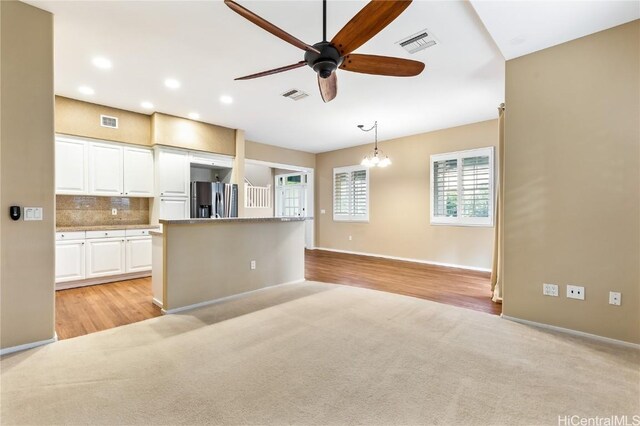 kitchen featuring ceiling fan with notable chandelier, decorative light fixtures, tasteful backsplash, white cabinetry, and stainless steel fridge with ice dispenser