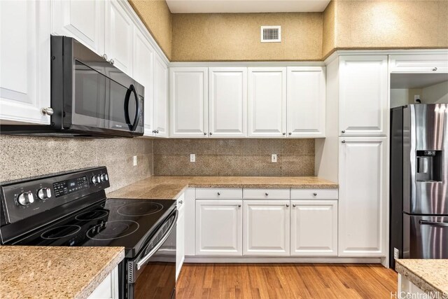 kitchen with black electric range oven, white cabinets, decorative backsplash, stainless steel fridge with ice dispenser, and light wood-type flooring