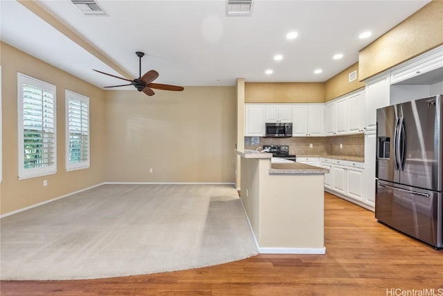 kitchen featuring light hardwood / wood-style flooring, ceiling fan, appliances with stainless steel finishes, white cabinetry, and backsplash