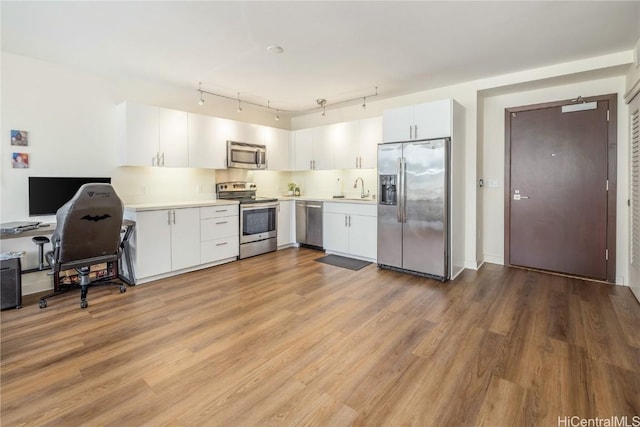 kitchen featuring white cabinetry, decorative backsplash, light hardwood / wood-style flooring, and appliances with stainless steel finishes