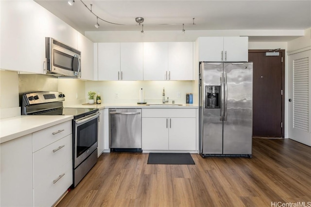 kitchen with dark wood-type flooring, appliances with stainless steel finishes, sink, and white cabinets