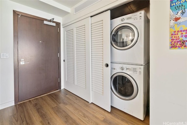 laundry area featuring stacked washing maching and dryer and hardwood / wood-style floors