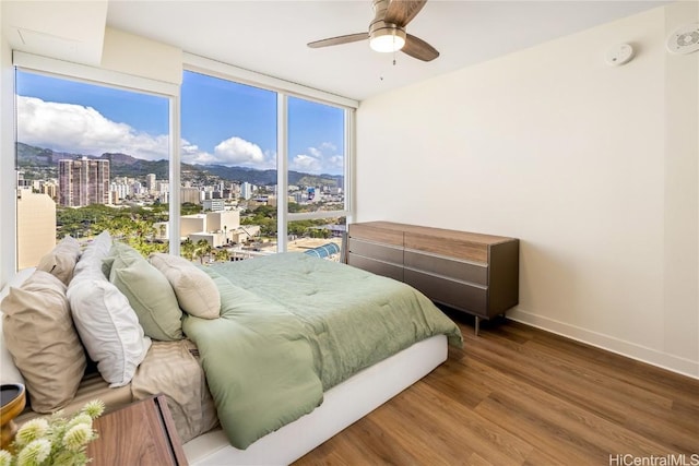 bedroom with hardwood / wood-style flooring, expansive windows, and ceiling fan