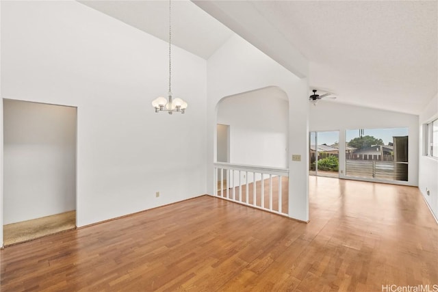 spare room with ceiling fan with notable chandelier, high vaulted ceiling, and light hardwood / wood-style floors