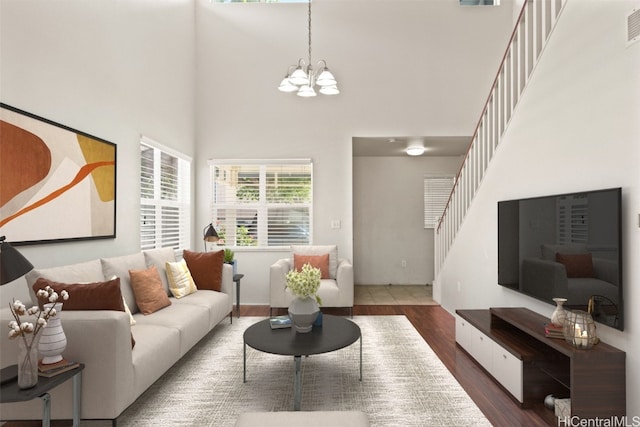 living room with dark hardwood / wood-style flooring, a towering ceiling, and a chandelier