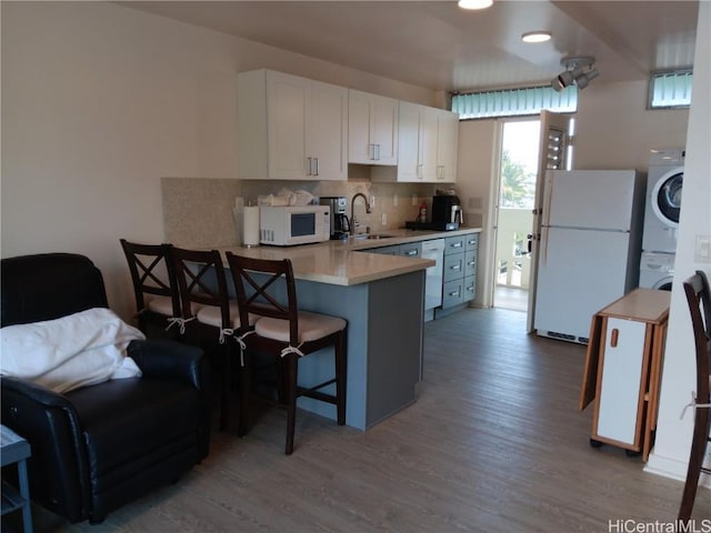 kitchen featuring light countertops, white cabinetry, a sink, white appliances, and a kitchen bar