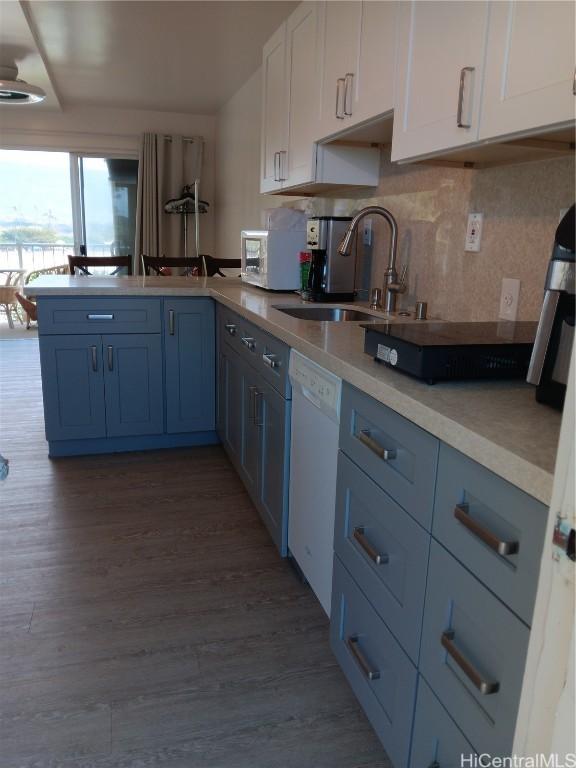 kitchen featuring light countertops, white cabinets, a sink, wood finished floors, and dishwasher