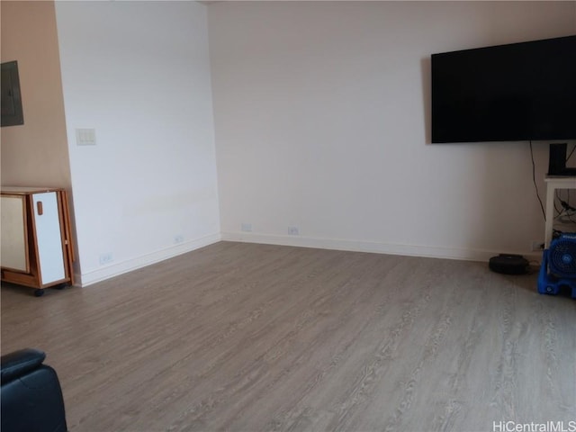 unfurnished living room with light wood-style floors, electric panel, and baseboards