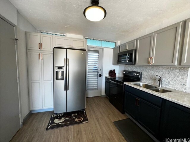 kitchen with tasteful backsplash, sink, light hardwood / wood-style flooring, and appliances with stainless steel finishes