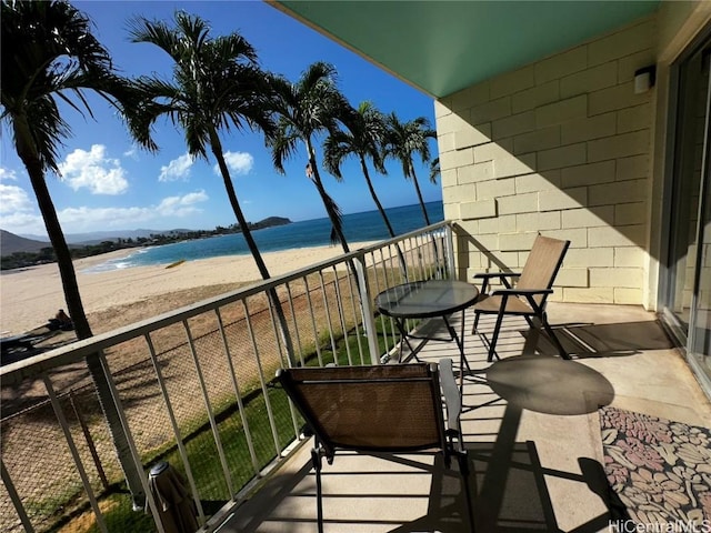 balcony featuring a view of the beach and a water view