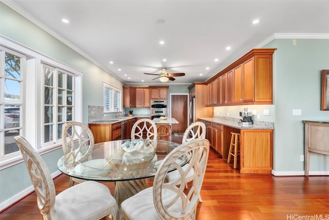 dining space with hardwood / wood-style floors, ornamental molding, and sink