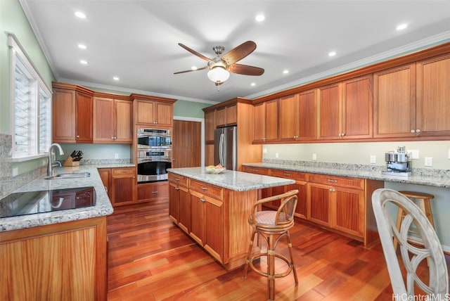 kitchen featuring light stone countertops, a kitchen island, sink, and appliances with stainless steel finishes