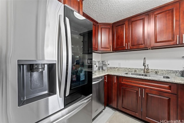 kitchen featuring stainless steel appliances, sink, a textured ceiling, and light stone counters