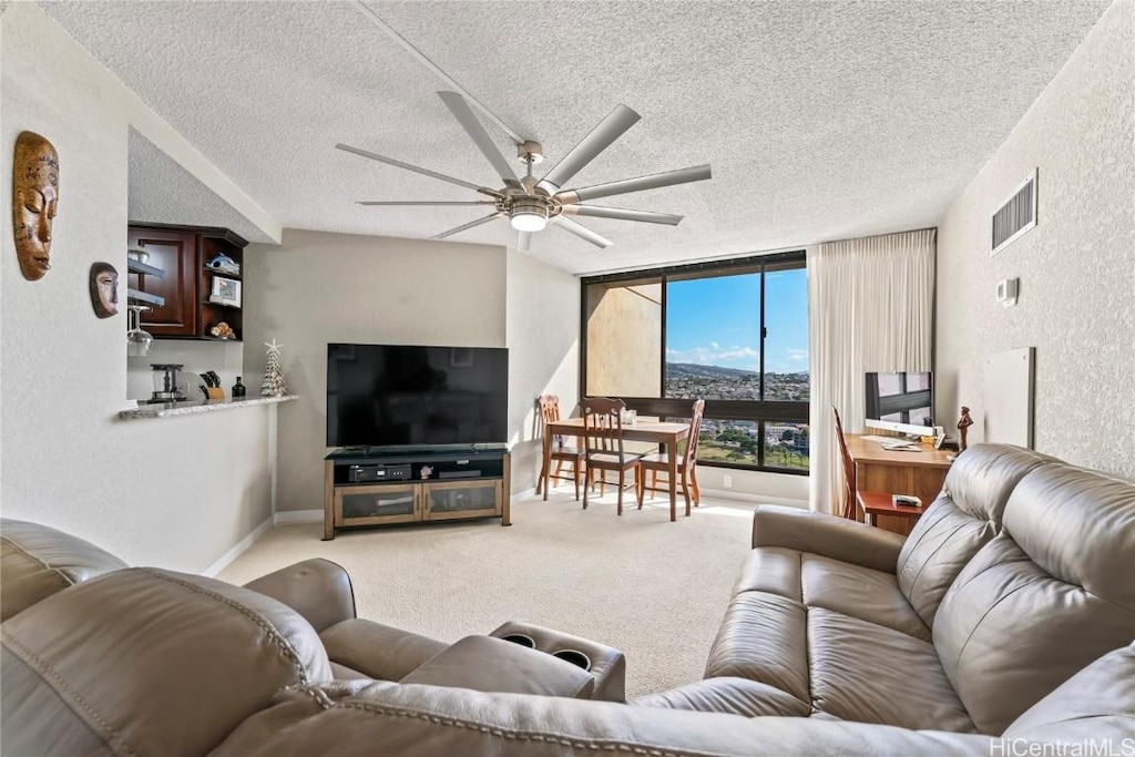 living room featuring ceiling fan, carpet floors, a textured ceiling, and a wall of windows