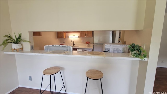 kitchen with a peninsula, white microwave, a sink, and freestanding refrigerator