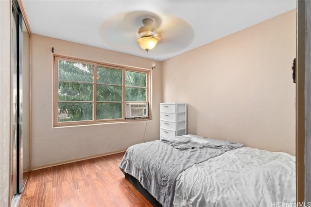 bedroom with cooling unit, ceiling fan, and light hardwood / wood-style flooring