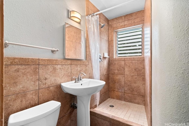 bathroom with tile walls, sink, curtained shower, and toilet