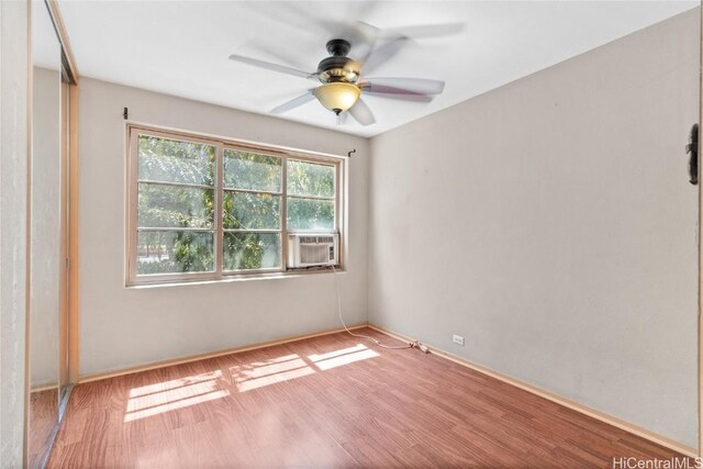 empty room with cooling unit, ceiling fan, and wood finished floors