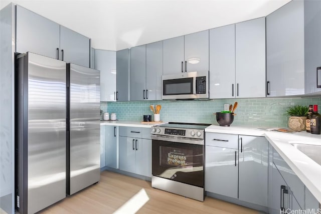 kitchen featuring appliances with stainless steel finishes, light wood-type flooring, and decorative backsplash