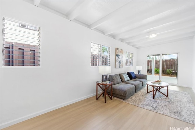 living area with baseboards, beamed ceiling, and wood finished floors