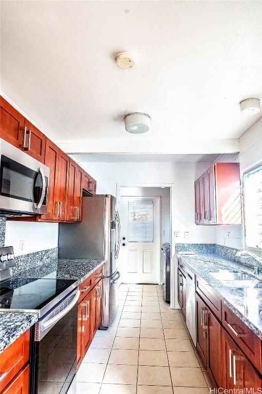 kitchen featuring sink, separate washer and dryer, light tile patterned floors, appliances with stainless steel finishes, and dark stone counters