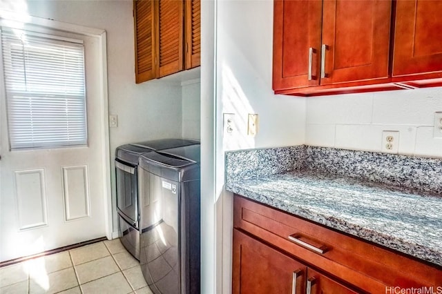 washroom with independent washer and dryer, light tile patterned floors, and cabinets