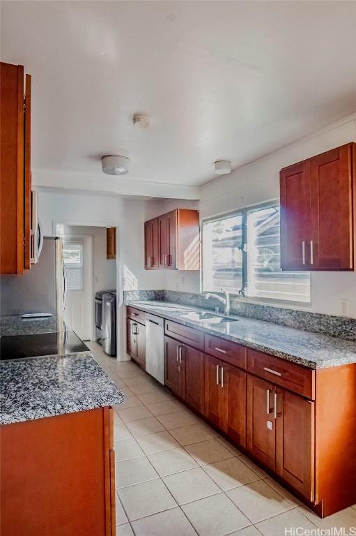 kitchen with dishwasher, sink, stove, light tile patterned floors, and light stone countertops