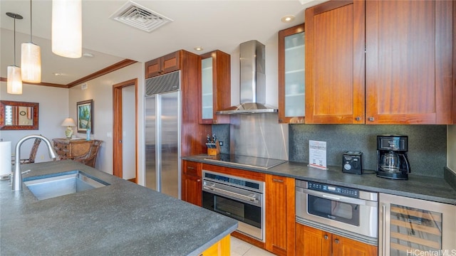 kitchen featuring sink, appliances with stainless steel finishes, decorative light fixtures, beverage cooler, and wall chimney exhaust hood