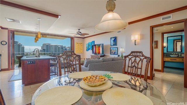 tiled dining space with ornamental molding, sink, and ceiling fan