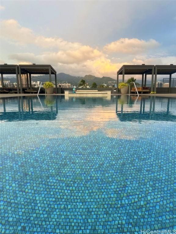 pool at dusk featuring a water view