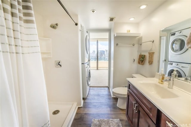 bathroom with stacked washer and dryer, toilet, vanity, curtained shower, and hardwood / wood-style flooring