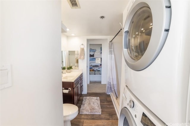 laundry room with stacked washer and dryer, sink, and dark hardwood / wood-style floors