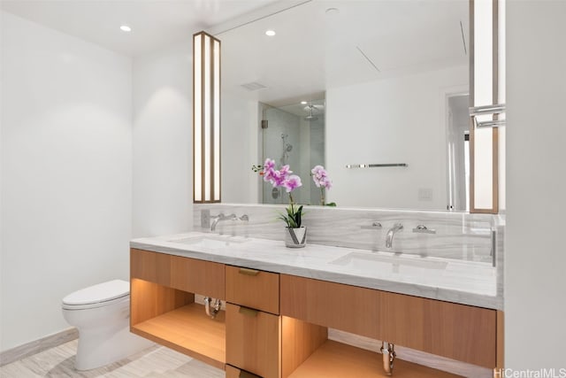 bathroom with vanity, toilet, a shower with door, and backsplash